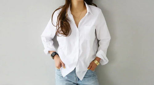 White long-sleeve button-down shirt worn by a model standing against a wall.