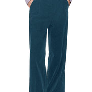 A person wearing high-waisted, wide-leg green corduroy trousers, styled with a light lavender ruffled shirt and black leather shoes,