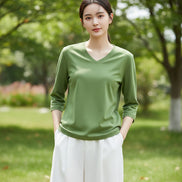 Person wearing a green V-neck shirt with a blurred background