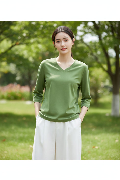 Person wearing a green V-neck shirt with a blurred background