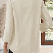 Person wearing a beige blazer in a room with a window in the background