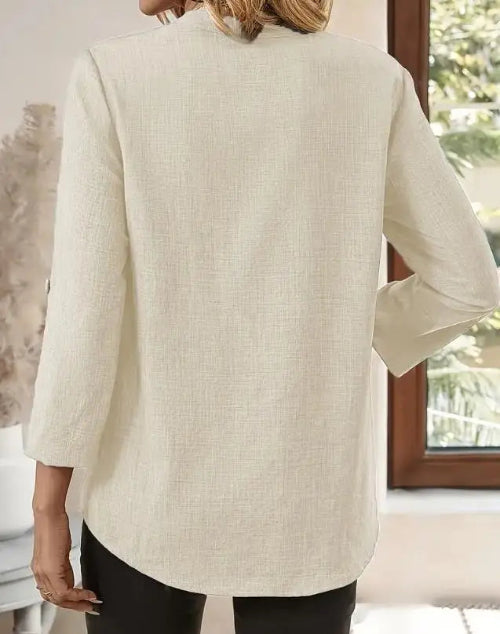 Person wearing a beige blazer in a room with a window in the background
