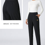 Black high-waisted slim-fit suit trousers shown on a model, with a close-up inset of the waistband and a small gold embroidered bee detail 