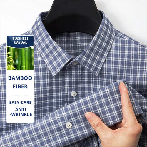 A close-up of a blue and white plaid button-down shirt on a black hanger, with a hand holding the folded cuff to show the fabric texture. A white promotional label on the left reads 'BUSINESS CASUAL', 