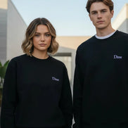 A person wearing a black crewneck sweatshirt with a small white embroidered 'Dime' logo on the left 