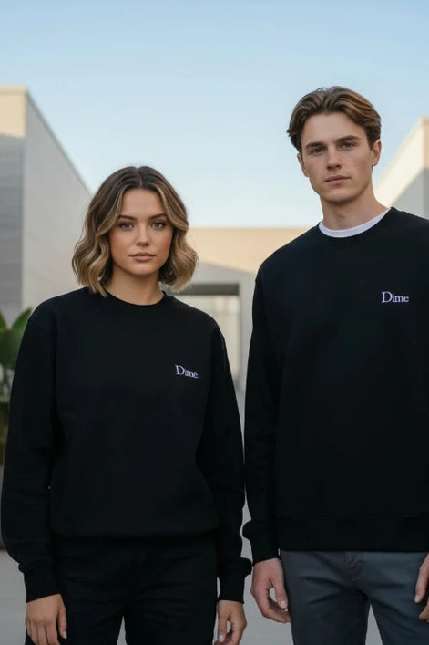 A person wearing a black crewneck sweatshirt with a small white embroidered 'Dime' logo on the left 