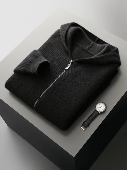 Folded black sweater with a watch on a gray surface