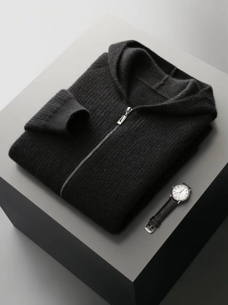 Folded black sweater with a watch on a gray surface