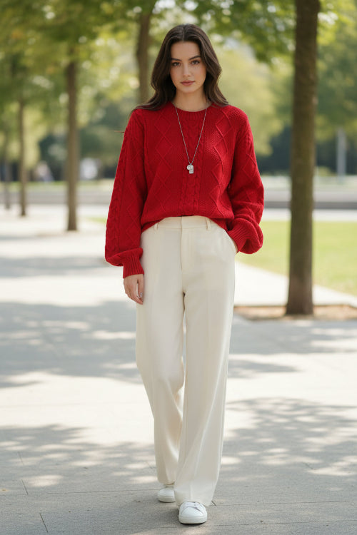 A person wearing a bright red cable-knit sweater with a crew neck and ribbed cuffs, 