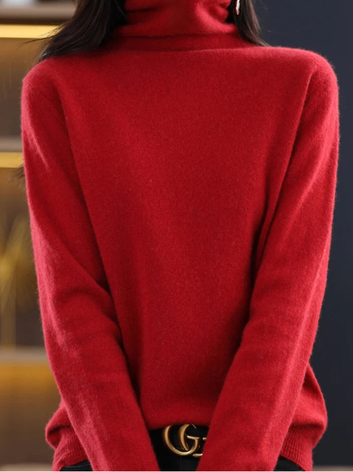 A close-up of a woman wearing a bright red, long-sleeve turtleneck sweater. The sweater is shown on a mannequin or model cropped from the nose down, 
