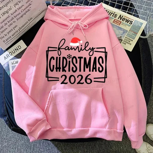 A pink pullover hoodie laid flat on a dark surface with newspaper props around it. 