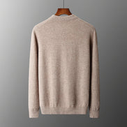 A light beige knit sweater displayed on a wooden hanger against a dark gray gradient background.