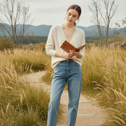 A person wearing a fuzzy off-white V-neck cardigan over a beige ribbed top, 