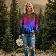 A woman wearing a long-sleeve crewneck sweatshirt with a vibrant galaxy and aurora print, paired with blue jeans and holding a bouquet of white roses.