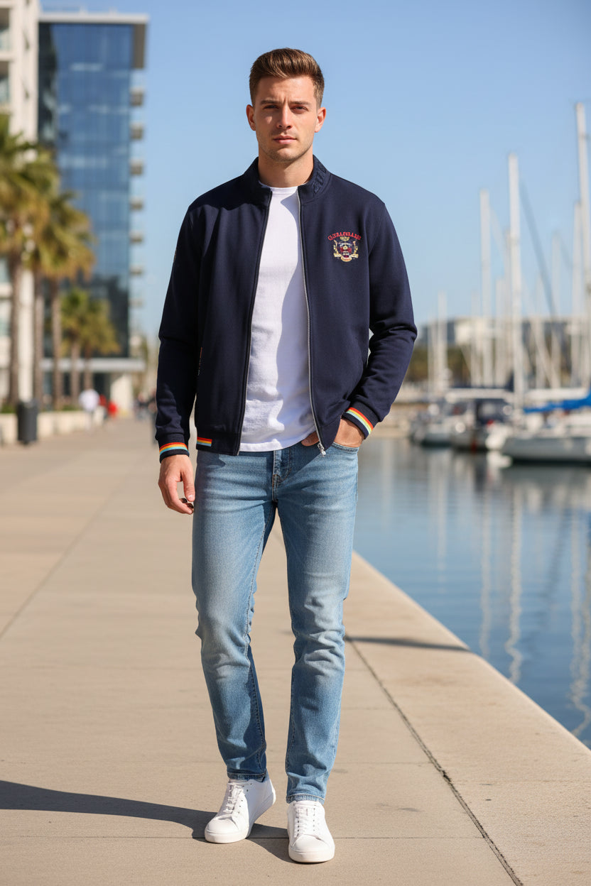 A navy blue zip-up jacket with multicolor striped ribbed cuffs and hem, featuring a crest on the left chest and a vertical 'FURYBAY' text print on the right sleeve. The TACE&SHARK brand logo is visible in the top-left corner.