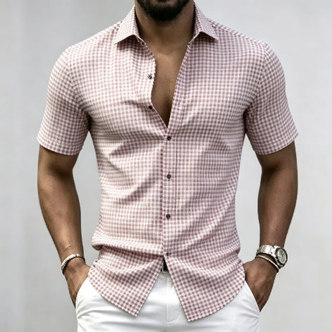 A man wearing a short-sleeve button-up shirt with a pink and white gingham check pattern, 