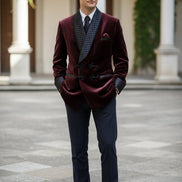 Man wearing a burgundy velvet suit with quilted lapels in a room with wooden paneling.