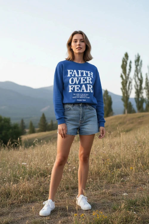 Blue sweatshirt with 'Faith Over Fear' text on a wooden background