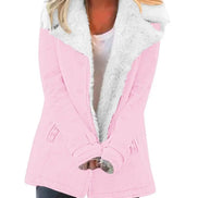 Woman wearing a pink coat with wide white fleece-look lapels, front pockets and cuff tabs over a white top and dark trousers