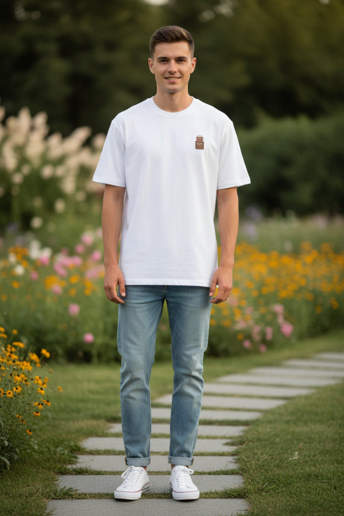 White t-shirt with a small brown and gold design on a hanger against a white background