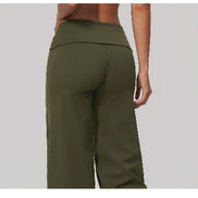 A close-up back view of a model wearing olive green wide-leg athletic pants against a light gray background.