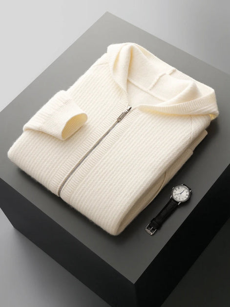 Folded cream-colored sweater on a dark surface with a watch and yellow object.