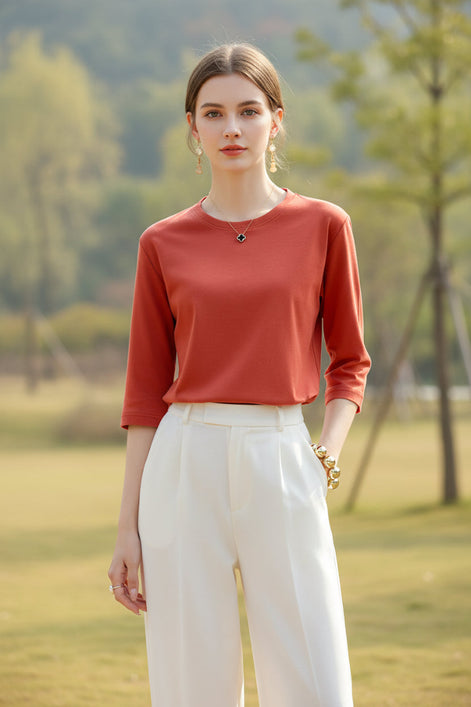 Person wearing a red long-sleeve top with a neutral background