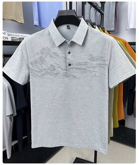 A light gray short-sleeve polo shirt with a subtle tonal landscape graphic across the chest, displayed on a black hanger in a retail setting.