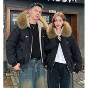 Two people wearing black jackets with fur hoods standing in front of a building.