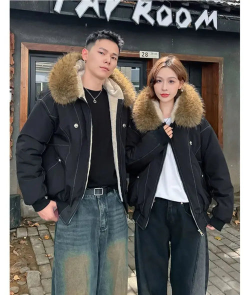 Two people wearing black jackets with fur hoods standing in front of a building.