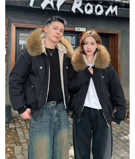Two people wearing black jackets with fur hoods standing in front of a building.