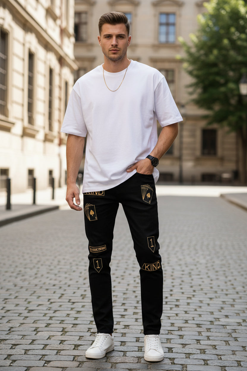 Black jeans with gold patches and branding on a white background