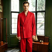 A man wearing a bright red double-breasted suit with a unique wrap-style collar, standing in a vintage room with dark green paneled walls and large windows.