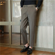 A person wearing slim-fit brown trousers, a black long-sleeve shirt, and black loafers