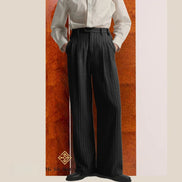 Person wearing a white shirt and black wide-leg pants against a wooden panel background