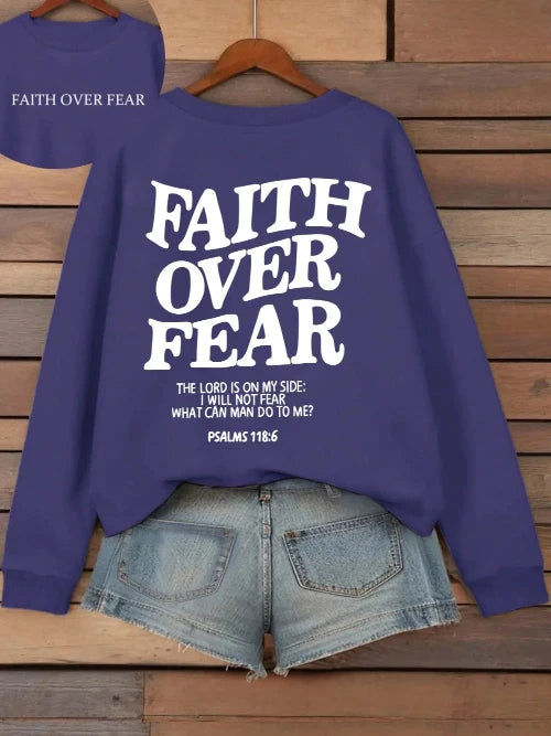 Purple sweatshirt with 'Faith Over Fear' text on a wooden background