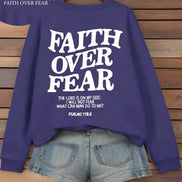 Purple sweatshirt with 'Faith Over Fear' text on a wooden background