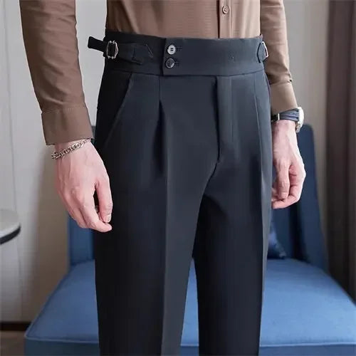 Person wearing dark gray pleated pants with a brown shirt in an indoor setting.