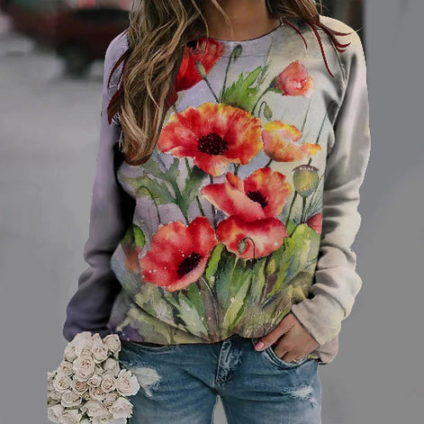 Person wearing a floral sweatshirt with red poppies and holding flowers.