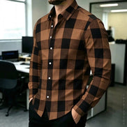 A man wearing a brown and black buffalo plaid long-sleeve button-down shirt in an office environment.