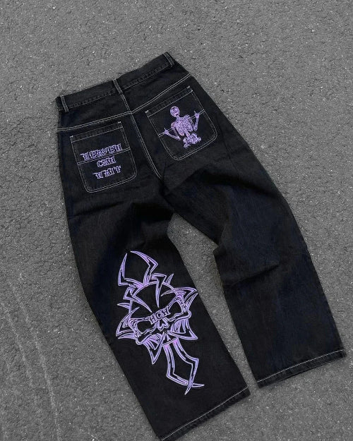 Front-angle view of a model wearing black wide-leg jeans with a black skull-design top and black sneakers against a white background.