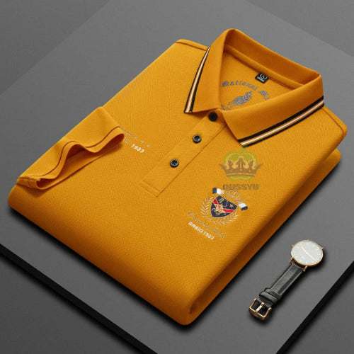 Yellow polo shirt with brand logos on a gray background, accompanied by a watch.