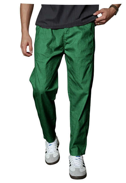 A person wearing bright green tapered pants with a dark gray t-shirt and white sneakers, shown from the waist down 