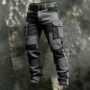 Olive green and black color-block cargo pants with flap thigh pockets and a black belt against a textured gray background.