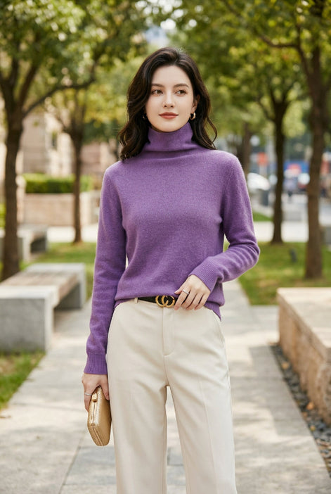 A woman wearing a fuzzy purple turtleneck sweater, paired with light beige pants and a black belt with a gold buckle, shown in a close-up shot.