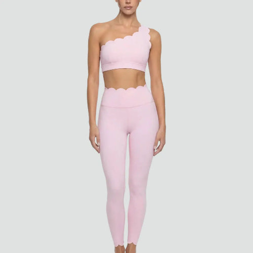 Person wearing a pink one-shoulder top and leggings on a light gray background