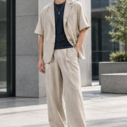 A two-piece neutral outfit set featuring a light beige short-sleeve blazer layered over a black t-shirt, 