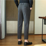 A person shown from the back wearing dark gray slim-fit trousers, a black long-sleeve shirt, and black loafers 