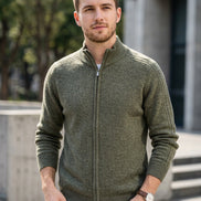 A gray knit zip-up sweater with a mock neck and ribbed cuffs and hem, hanging on a wooden hanger against a light gray background. 