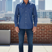 Man wearing a blue denim shirt with a city skyline in the background